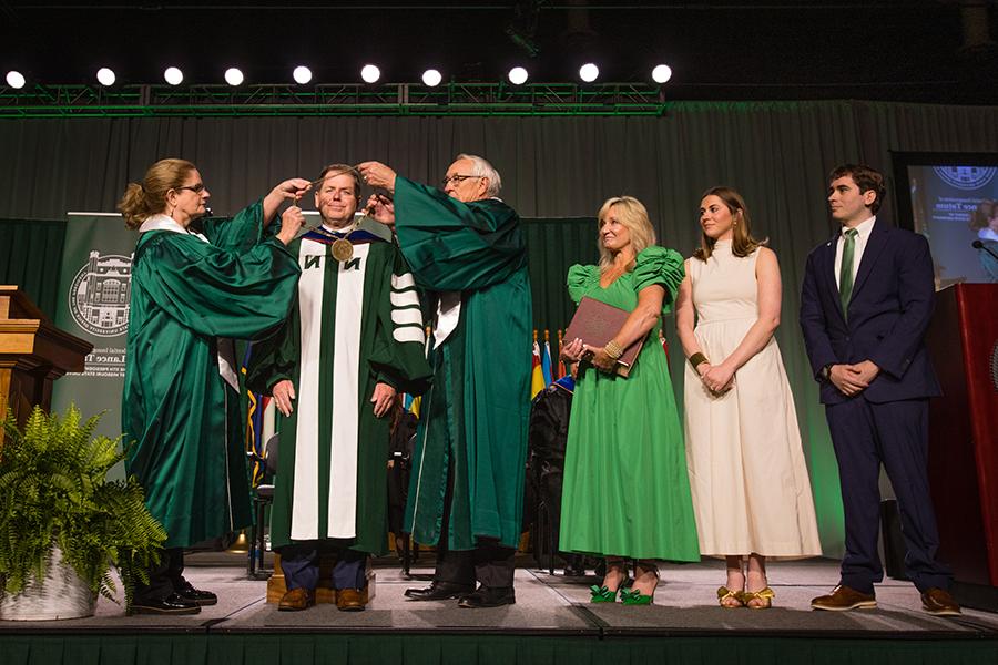 Northwest Regents Mel Tjeerdsma 和 Roxanna Swaney placed the University's chain of office on Dr. 兰斯·塔图姆的肩膀，他的家人在一旁看着. (Photo by Lauren Adams/<a href='http://ddfnaz.yn17car.com'>和记棋牌娱乐</a>)